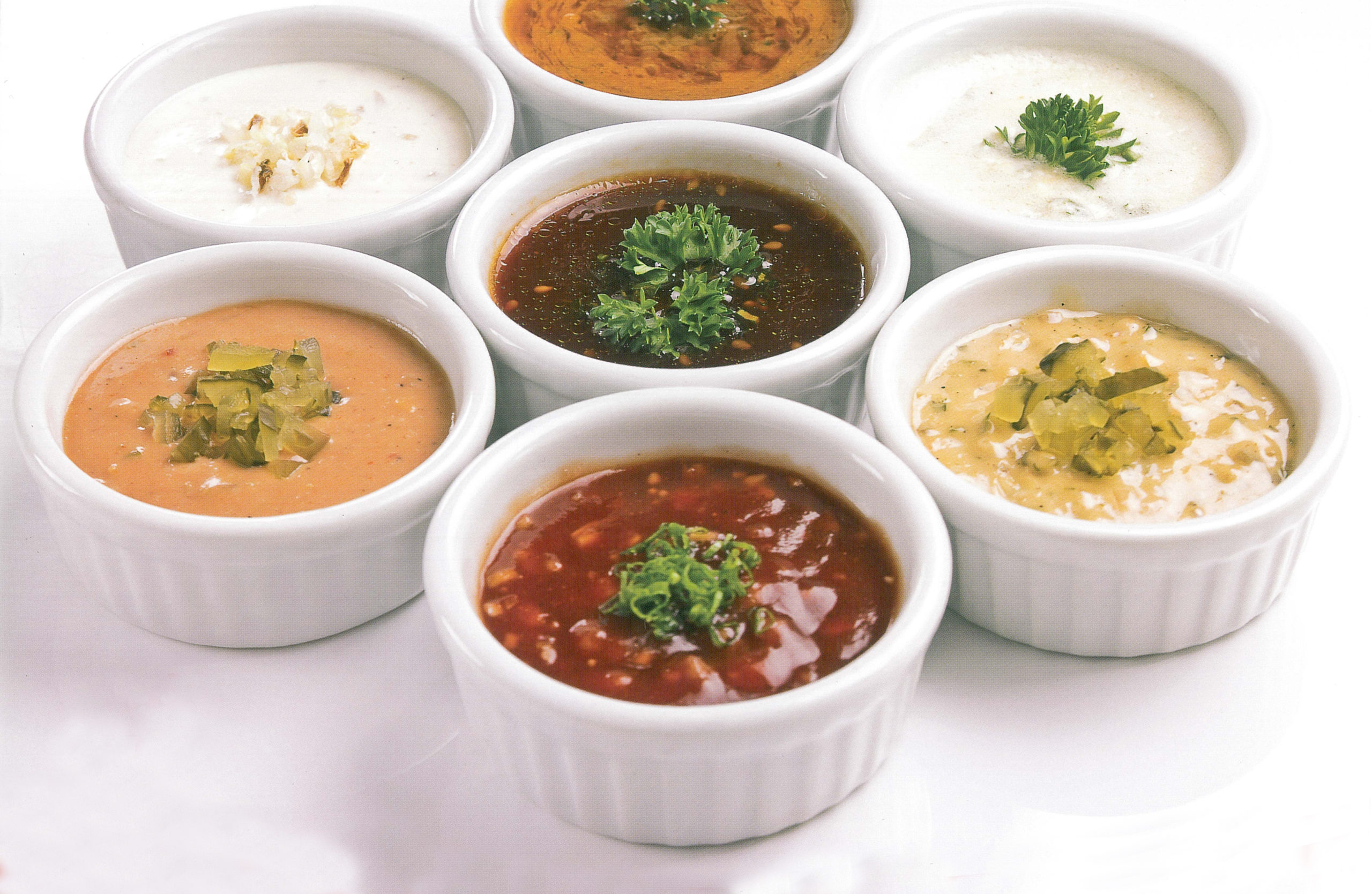 photo of several white ramekin, each holding a different sauce
